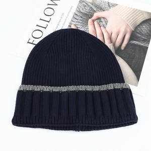 Detailed view of navy blue ribbed knit winter beanie with light gray stripes
