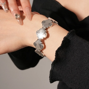 Vue détaillée d'un bracelet vintage en argent avec breloques trèfle gravées et ciselées
