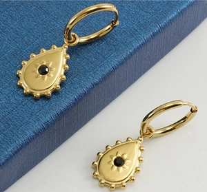 Close-up of 18K gold teardrop earrings featuring black stones and starburst pattern