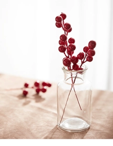 Close-up of vibrant red Christmas berry stems in a glass vase for festive home decoration