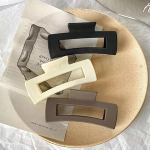 Set of three matte square hair claw clips in black, beige and brown on ceramic plate