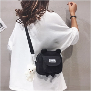 Detailed back view of black canvas crossbody bag with cute white bear plush charm