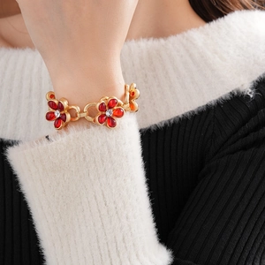 Detail of vintage gold flower bracelet with red stones and crystals on model's wrist