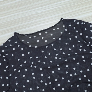 Detail showing the crew neck design and sheer polka dot mesh fabric of the women's top
