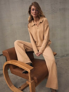 Detail of knitted polo sweater and wide-leg pants set in beige shown on a wooden chair