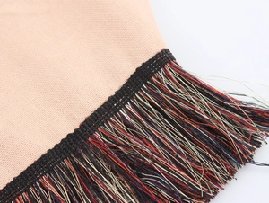 Dettaglio macro delle nappe in stile etnico e dell'orlo in tessuto a maglia boho