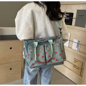 Detailed back view of a mint green tote bag with cherry print and multi-pocket design