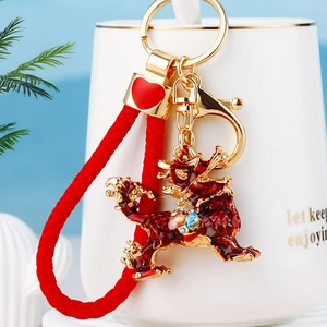 Detail of red enamel Kirin keychain with crystals hanging on a white mug edge