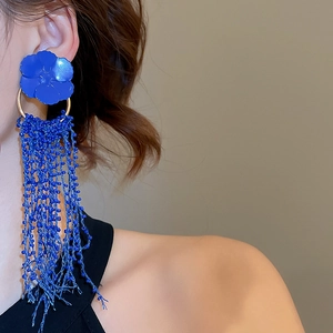 Close-up of royal blue tassel earrings with flower stud on model in profile view