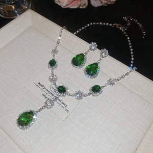 Dettaglio della collana con ciondolo a goccia smeraldo e orecchini con riflessi brillanti
