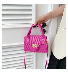 Macro detail of magenta quilted small square handbag with golden twist lock and V-stitch pattern