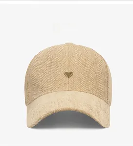 Detail of beige baseball cap with metal heart PARIS logo on herringbone fabric