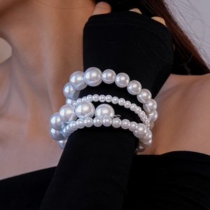 Gros plan sur un bracelet baroque à trois rangées de perles d'imitation de tailles variées