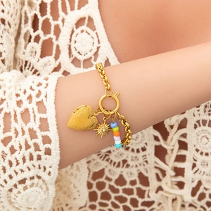 Detail of 18K gold bracelet with vintage heart locket, sun charm and colorful beads