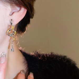 Detailed close-up of snake-shaped silver earrings with amber zircons and crystal drop charm
