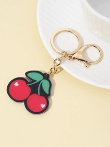 Macro detail of red cherry keychain with green leaves and golden lobster clasp