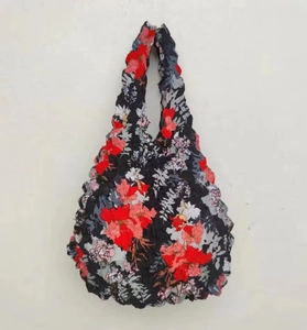 Detail of expandable black pleated tote bag with red and gray floral patterns