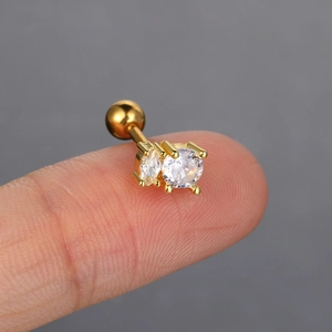 Close-up of gold geometric zircon cartilage stud earring held on a fingertip