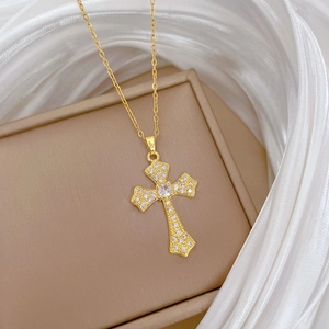 Macro shot of gold cross necklace with shimmering zircon crystals on brown jewelry box