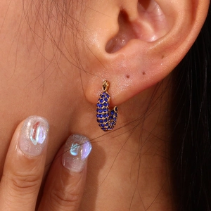 Macro shot of 18K gold plated hoop earring with pavé-set blue zircons on model ear