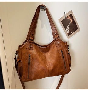 Detail of caramel tote bag with double handles and side pockets on a white wall