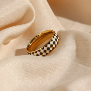 Macro shot of 18K gold plated ring with black and white checkered enamel on beige silk