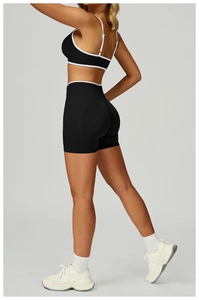 Detailaufnahme der Kontrastpaspelierung am schwarzen Sport-BH und der High-Waist Yoga-Shorts