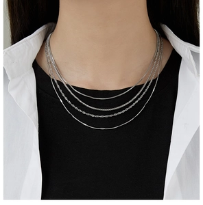 Detail of layered silver stainless steel chain necklaces worn by a model in close-up shot