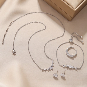 Flat lay of a luxury silver jewelry set with zircon clusters on elegant satin fabric