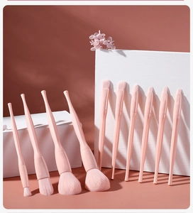 Detailed view of twelve professional pink makeup brushes arranged on white geometric blocks