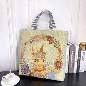 Detail of vintage floral and rabbit jacquard patterns on canvas tote bag with striped handles