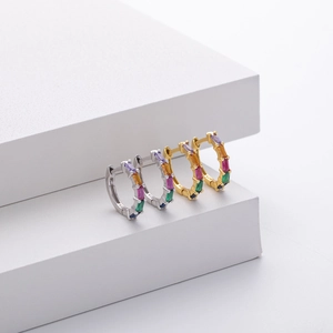 Detailed macro view of silver and gold huggie hoops with rectangular rainbow gemstones
