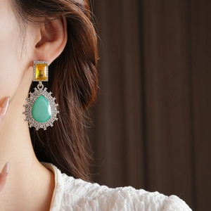 Gros plan de boucles d'oreilles vintage avec pierres jaunes et pendentifs goutte vert menthe
