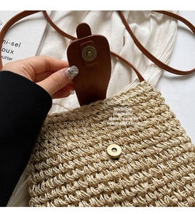 Detail of the hidden magnetic snap on a straw woven crossbody bag with leather flap