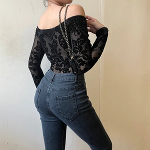 Detail of black floral lace fabric on an off-shoulder bodysuit with sheer long sleeves