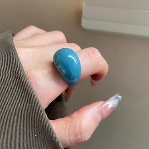Blue resin oval ring on finger showing glossy surface and minimalist geometry