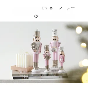 Set of four pink and silver nutcracker soldier figurines on a decorative book
