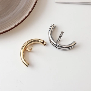 Detail of minimalist gold and silver metal ponytail cuffs with smooth polished finish