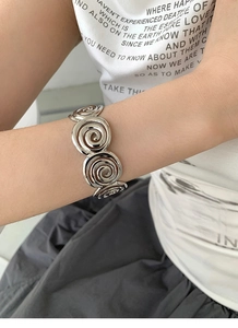 Detailed close-up of a silver geometric spiral bangle showing polished metal texture on wrist