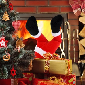 Santa Claus legs decor placed on a gold gift box by a cozy fireplace and Christmas tree