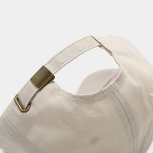 Detalle del cierre ajustable de hebilla de metal bronce en la gorra de algodón beige