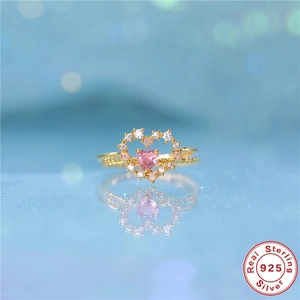 Detail of S925 sterling silver ring with pink heart stone and tiny clear gems on blue background
