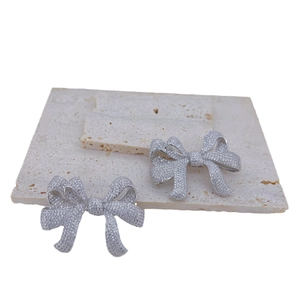 Bow-shaped jewelry clasp accessory with micro-pave crystals on beige stone base