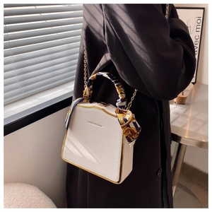 Detailed shot of white mini box bag with gold metal frame and floral silk scarf handle