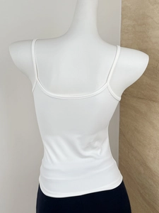 Detailed back view of a slim-fit white camisole top with thin straps on a model
