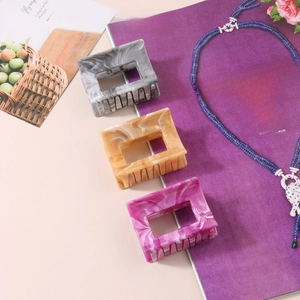 Detail of marble-patterned acetate hair claws in grey, brown, and purple finishes