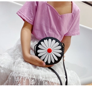Detail of a round black leather children's bag featuring a large white daisy flower applique