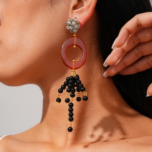 Détail de boucles d'oreilles bohèmes avec cristaux gris et anneaux en résine ambrée