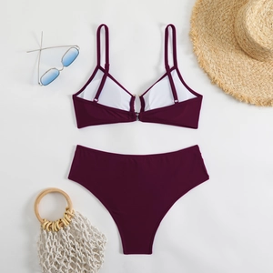 Flat lay of a burgundy bikini set with high-waist bottoms and stylish beach accessories