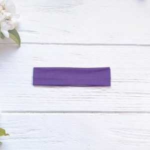 Detailed texture of high-elasticity purple yoga headband on rustic white wood background